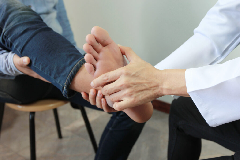 Closeup of Man feeling pain in her foot and doctor the traumatologist examines or treatment on white background, Healthy concept – Mash Spine & Orthopaedics